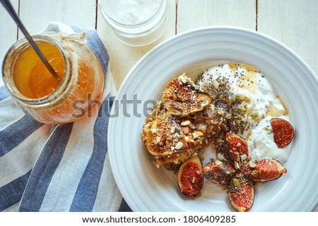 Flat lay baked oatmeel with figs and nuts, yogurt and and honey on white table at sunlight morning. healthy breakfast at home, cozy food picture.