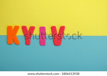 Top view of textured letters with Kyiv lettering on blue and yellow flag of Ukraine, colorful letters, Kyiv is written on colorful background 