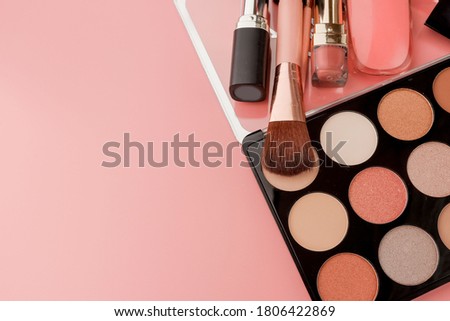 Various makeup productson pink background with copyspace.