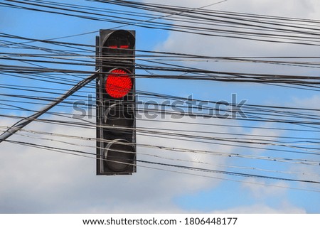 Traffic light behind many electrical wires against the background of the sky