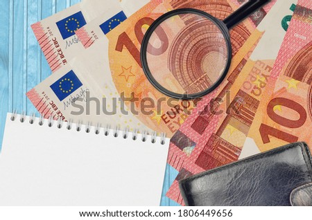 10 euro bills and magnifying glass with black purse and notepad. Concept of counterfeit money. Search for differences in details on money bills to detect fake