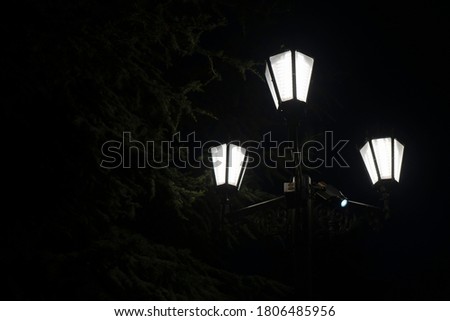 Burning lantern with three shades at night in the park.