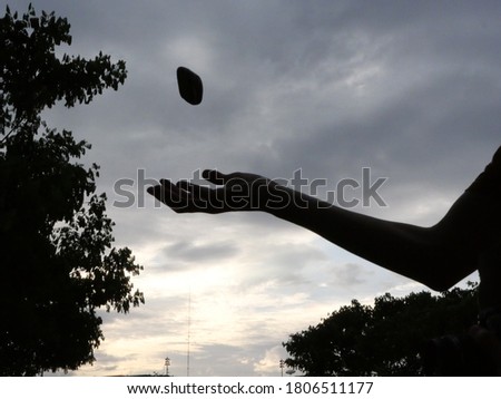 Silhouette picture of a man throwing a rock.