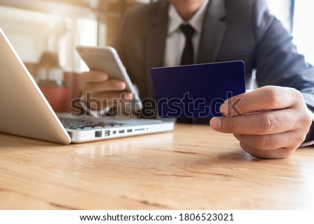Businessman hand holding credit card and use laptop and smartphone in office.