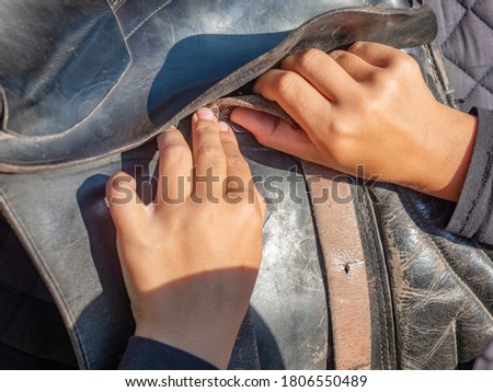 Girl set leather strips of lower abdomen and stirrups before riding. 