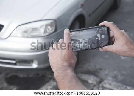 Man taking photo of a car on his phone.