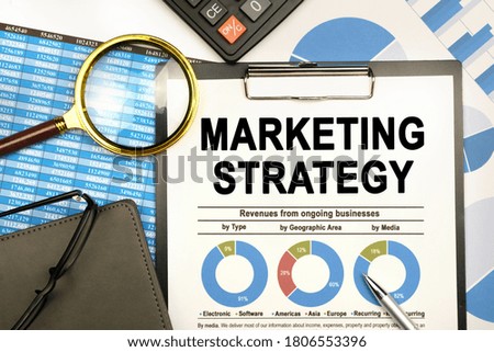 Finance and business concept. The businessman has on his desk graphs with reports, a notebook, a magnifying glass and a document with the inscription - MARKETING STRATEGY