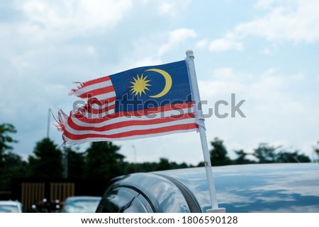 A picture of torn waving Malaysia low quality flag at the park. Symbol of less patriotic.