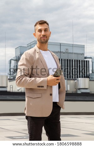 A man in a jacket holds a phone in his hands.