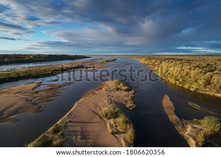 Top view of the sandy islands with green bushes and grass against the background at sunset light. The shallows at the bottom of the river. Abstract landscape with drone at autumn