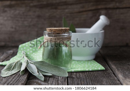 Fresh sage leaves and glass jar of sage oil.