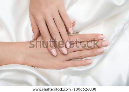 Female hands with pink nail design. Pink nail polish manicured hands. Female hands on white fabric background