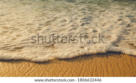 Scenic seascape. Milky foam waves at sandy beach. Sunset time. Waterscape for background. Selected soft art focus. Sunlight reflection on the water and wet sand. Balangan beach, Bali, Indonesia