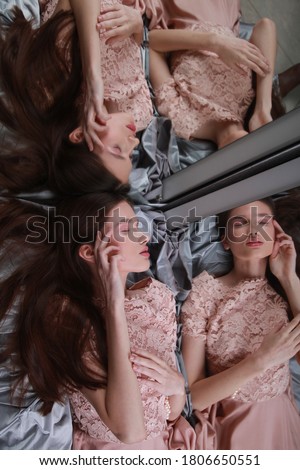 
Fashion, evening dresses for events. Young teenage model in pink lace dress lying with closed eyes near mirrors, which tripples her reflection