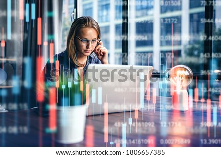 Young woman working at modern office.Technical price graph and indicator, red and green candlestick chart and stock trading computer screen background. Double exposure. Trader analyzing data Royalty-Free Stock Photo #1806657385