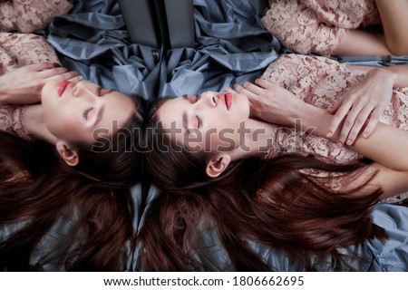 Concept of a sleeping beauty. Pretty girl in a pink lace dress lying on a fabric near the mirrors. Mysterious image with few reflections of a beautiful girl with closed eyes lying. High angle view