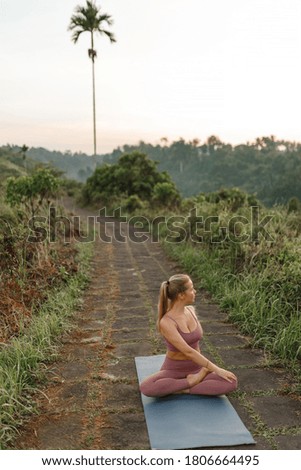 Young woman in sports wear exercising in park, sit on yoga mat and stretching