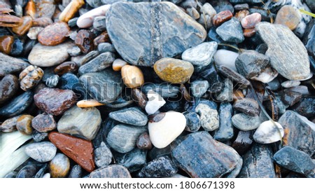 Stony beach on a sunny day. Background of different pebbles from above on the beach