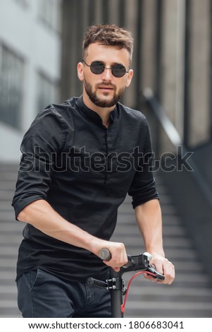 Young man riding electric scooter in urban background
