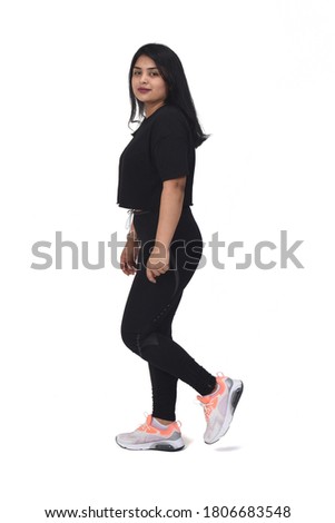  side view of a latin woman walking with sportswear looking at camera on white background,