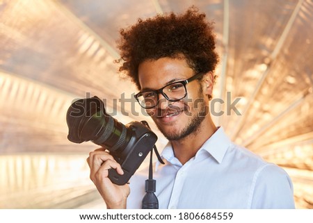 Smiling young photographer with reflex camera in the photo studio