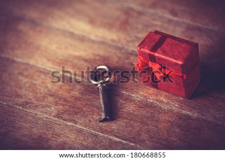 Retro key and little red gift on wooden table.