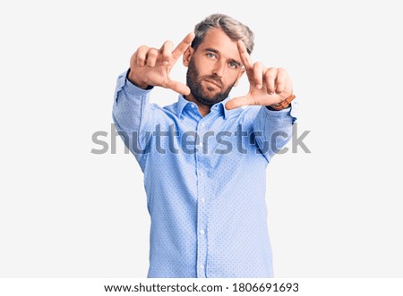 Young handsome blond man wearing elegant shirt doing frame using hands palms and fingers, camera perspective 