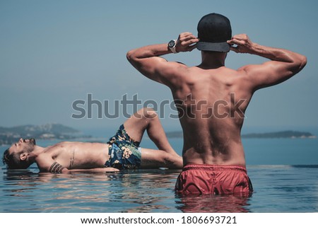 Two men on vacation sunbathing by the pool. Royalty-Free Stock Photo #1806693721