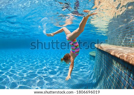 Funny portrait of child learning swimming, dive in blue pool with fun - jumping deep down underwater with splashes. Healthy family lifestyle, kids water sports activity, swimming lesson with parents. Royalty-Free Stock Photo #1806696019