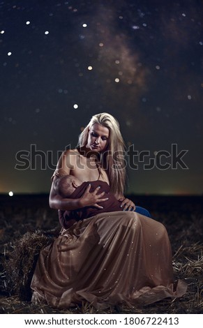 Woman breastfeeding her son under Milky Way lit sky
