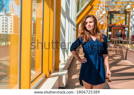 Portrait of a beautiful young business woman in a bright creative space with yellow metal frames on the Windows