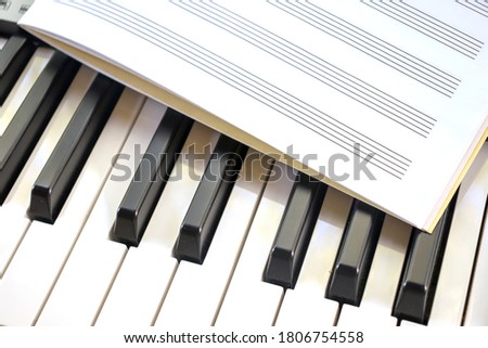 Notebook lies on black and white piano keys studying musical roughness of notes pianist music on synthesizer