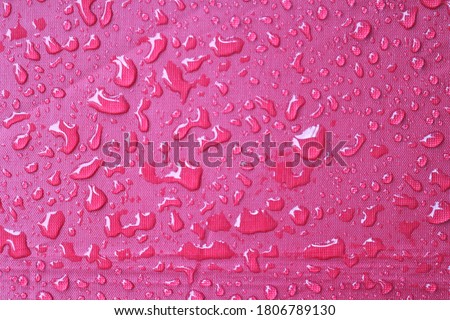 Water droplets​ land on​ the surface of the red umbrella 