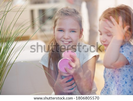 Two smiling children with finger paints in pots