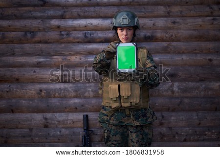 woman soldier using tablet computer  against old wooden  wall in camp
