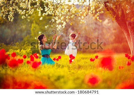  Happy woman and child in the blooming spring garden.Mothers day holiday concept Royalty-Free Stock Photo #180684791