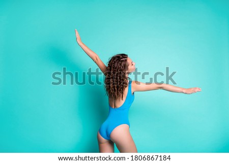 Back rear view photo of slim lovely young lady curly hairstyle show star plane figure enjoy rest relax sea ocean waves wings fly wear blue swimsuit isolated turquoise color background