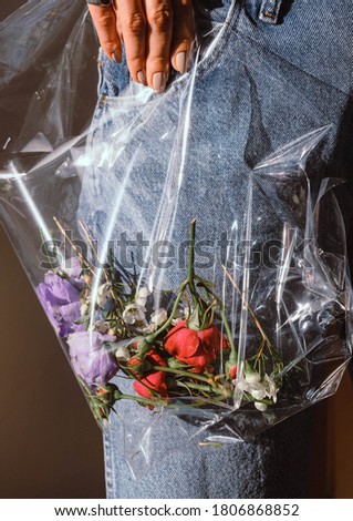Roses and other flowers in plastic bag, flower decor in plastic ecology concept photo.