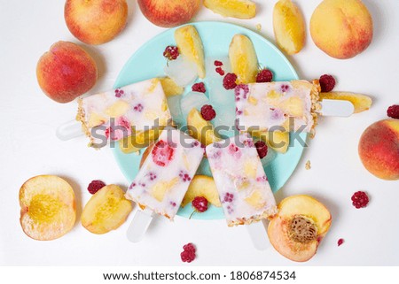 fresh summer ice cream on a stick with peach and raspberry berries . on light background.