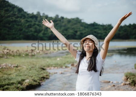 Asian young woman having enjoy and relaxing with nature, field of water stream, waterfall outdoor