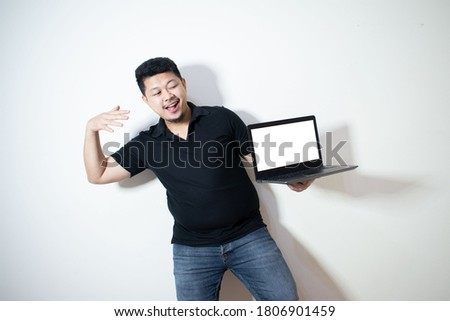 Young Asian in black polo Holding a smartphone and laptop
In a white background
