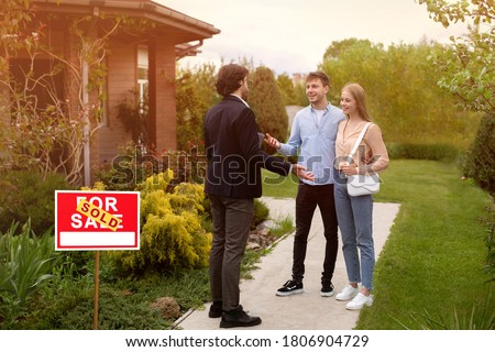 Real estate broker and new home owners in front of their property outside