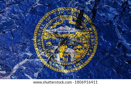The US National Flag of Nebraska is a blue canvas with the center of the state seal, made of gold and silver for Independence Day on a mountain wall. Rock graffiti of climbers during the ascent.