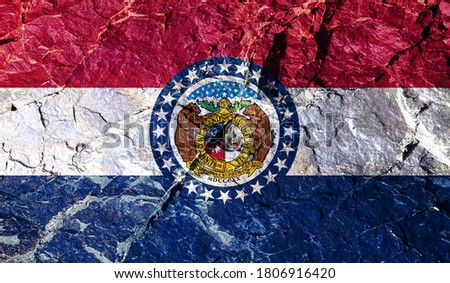 National flag of American state of Missouri, background of red, blue and white stripes, circular emblem with two bears and stars painted on mountain wall. Rock graffiti of climbers during the ascent.