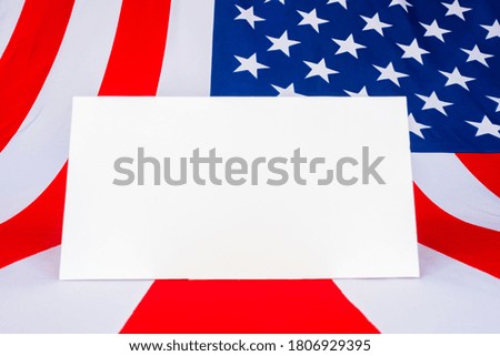 A sheet of paper on the background of the American flag. Mockup with the American flag. Flag of the United States of America and white space for text . Patriotic American frame.