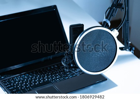 Laptop and microphone close-up. The usual set for voice work. Professional black microphone on a tripod. Black-and-white concept of recording.