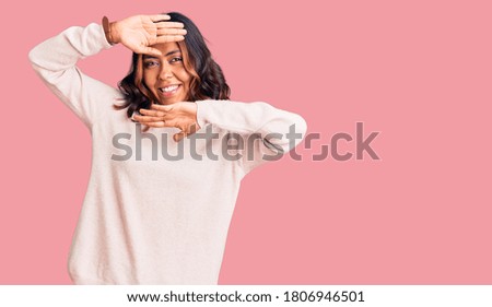 Young beautiful mixed race woman wearing winter turtleneck sweater smiling cheerful playing peek a boo with hands showing face. surprised and exited 