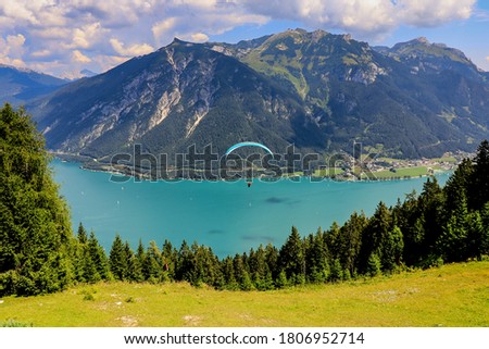 A paraglider over Achen lake, a picturesque alpine  lake with shimmering turquoise waters , offering swimming, sailing, boating and hiking. A view from cable car station above Pertisau.  Austria Royalty-Free Stock Photo #1806952714