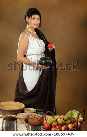 Young Romana with bowl and basket full of fruits and vegetables. Concept studio portrait on brown background.