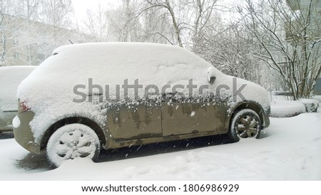 Snow covered car. Winter is here. Protection of vehicle against corrosion and salt. Clearing auto of ice. Snowfall in city. Frosty cold weather, blizzard, snowstorm. 
